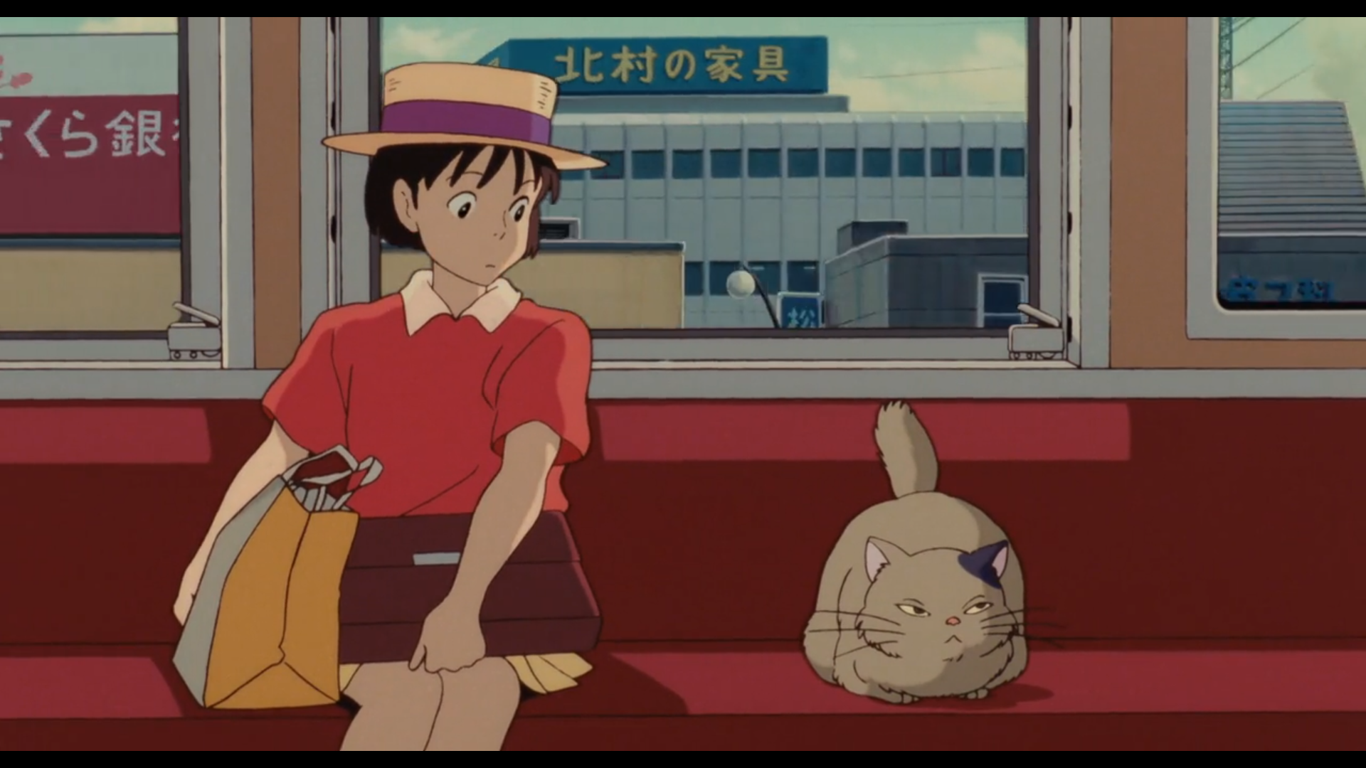 Scène de Si tu tends l'oreille
Shizuku, adolescente japonaise, cheveux noirs, yeux noirs, habillée d'un haut rouge, d'une jupe jaune et d'un chapeau couleur paille avec un ruban violet, avec un sac en papier posé à coté d'elle et un porte-document en cuir sur les genoux, est assises sur une banquette de métro de couleur pourpre. Elle observe avec un air curieux un chat assis à sa gauche, au pelage marron, l'oreille gauche noire, les yeux jaunes à moitié ouverts.
A travers les fenêtres, on aperçoit des bâtiments en béton, avec des panneaux bleu et rouge en japonais.